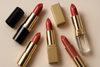 “A luxury beauty editorial banner showcasing premium lipsticks in elegant shades, arranged artistically on a soft, minimal background. Close-up focus on rich, creamy textures and vibrant colors, with subtle gold or glass accents to evoke sophistication. Clean lighting, modern and aspirational style, similar to Sephora campaign visuals.”